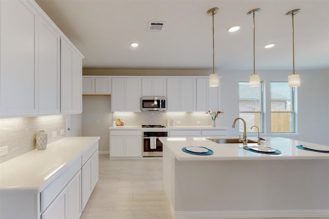 kitchen with visible vents, a sink, white cabinetry, appliances with stainless steel finishes, and light countertops