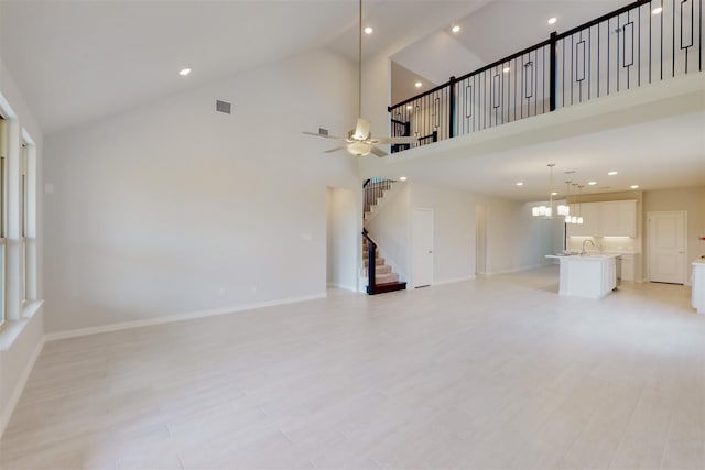 unfurnished living room with stairway, light wood-style flooring, and baseboards