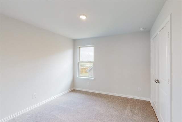 unfurnished bedroom with baseboards, a closet, and light carpet