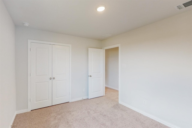 unfurnished bedroom with visible vents, baseboards, light colored carpet, and a closet