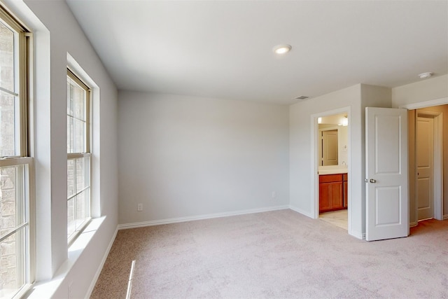 unfurnished room with visible vents, a healthy amount of sunlight, light colored carpet, and baseboards