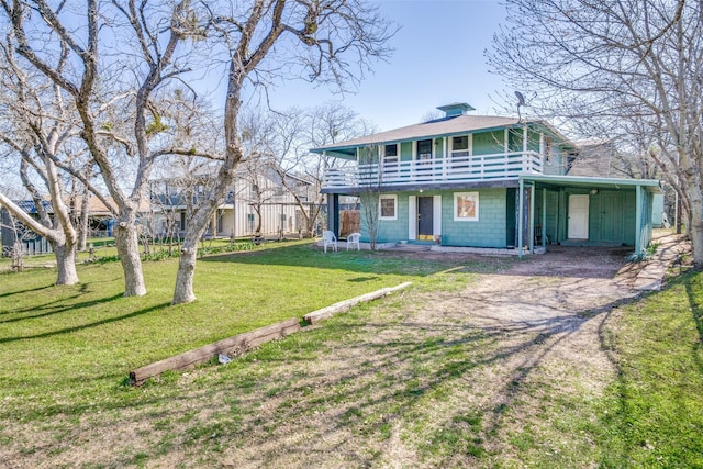 view of front facade featuring driveway, a balcony, and a front lawn