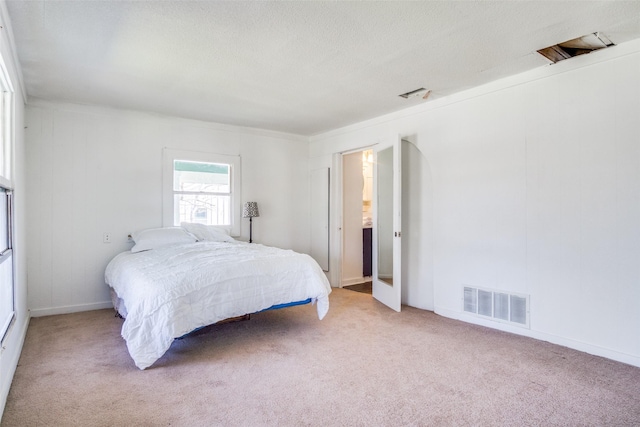 bedroom with light carpet, visible vents, and a textured ceiling