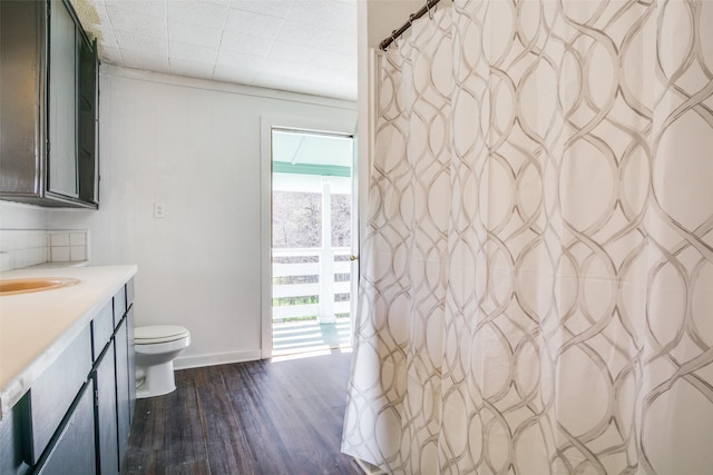 bathroom with vanity, toilet, wood finished floors, and baseboards