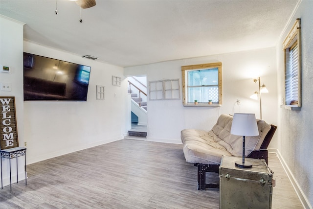 sitting room with visible vents, baseboards, wood finished floors, and stairs