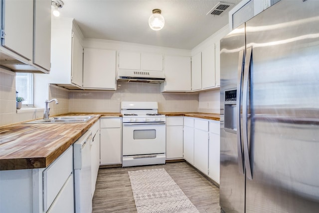 kitchen featuring visible vents, under cabinet range hood, butcher block countertops, white appliances, and a sink