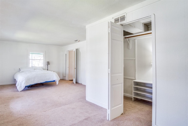 bedroom with light carpet, visible vents, a walk in closet, and a closet