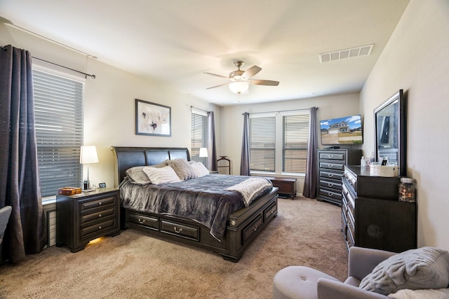 bedroom with a ceiling fan, light colored carpet, and visible vents