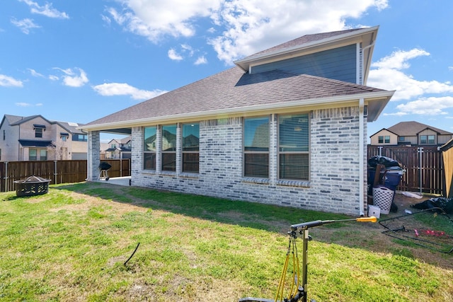 rear view of house featuring a fenced backyard, brick siding, and a lawn