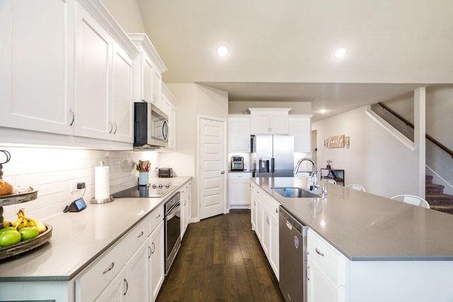 kitchen with recessed lighting, a kitchen island with sink, a sink, stainless steel appliances, and dark wood-type flooring