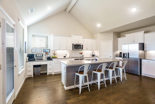 kitchen with visible vents, a sink, a center island with sink, stainless steel appliances, and dark wood-style flooring