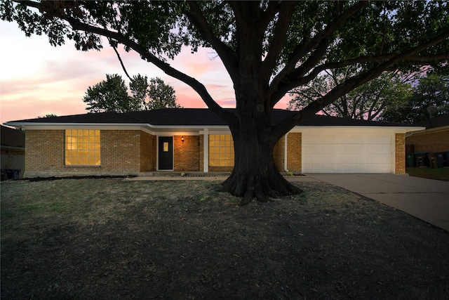 ranch-style home featuring a yard, brick siding, concrete driveway, and an attached garage