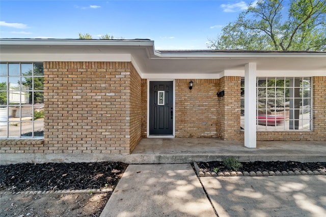 entrance to property with brick siding and a porch