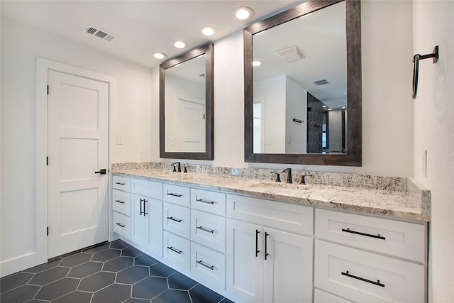 full bath featuring double vanity, visible vents, and a sink