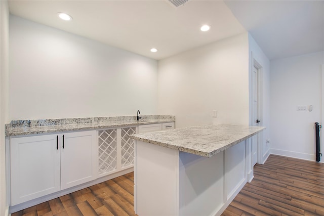 kitchen with dark wood finished floors, a peninsula, recessed lighting, a sink, and white cabinetry