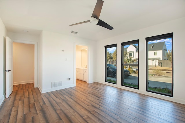 unfurnished bedroom featuring visible vents, multiple windows, baseboards, and wood finished floors