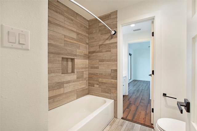 bathroom with bathtub / shower combination, toilet, wood finished floors, and visible vents