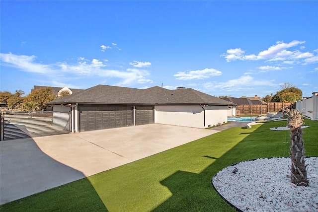 exterior space featuring a fenced in pool, fence private yard, a lawn, a garage, and driveway