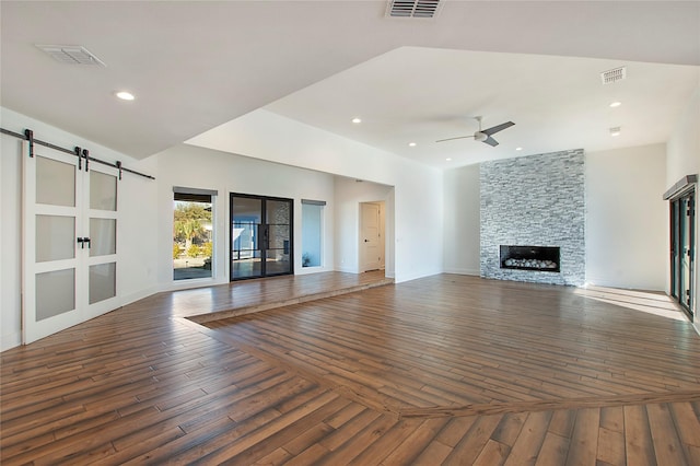 unfurnished living room featuring visible vents, a barn door, and a fireplace