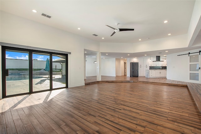 unfurnished living room with visible vents, recessed lighting, a barn door, light wood-style floors, and ceiling fan