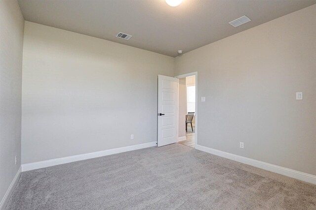 empty room with light colored carpet, visible vents, and baseboards