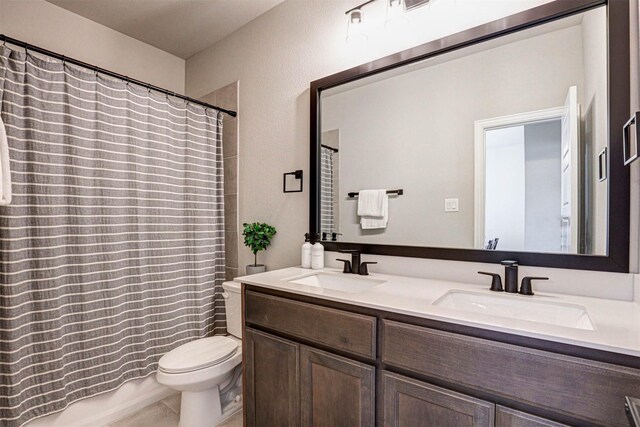 full bathroom with a sink, double vanity, and toilet