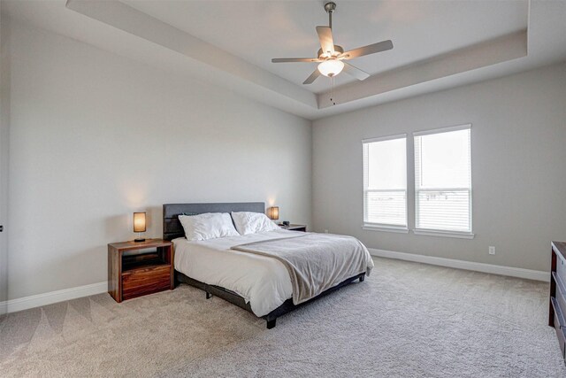 bedroom with light carpet, baseboards, a raised ceiling, and ceiling fan