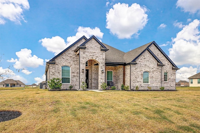 french country style house featuring brick siding and a front lawn