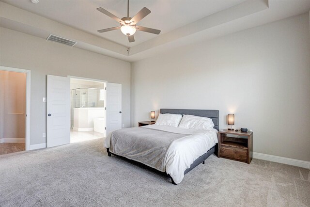 bedroom with a tray ceiling, carpet floors, baseboards, and visible vents