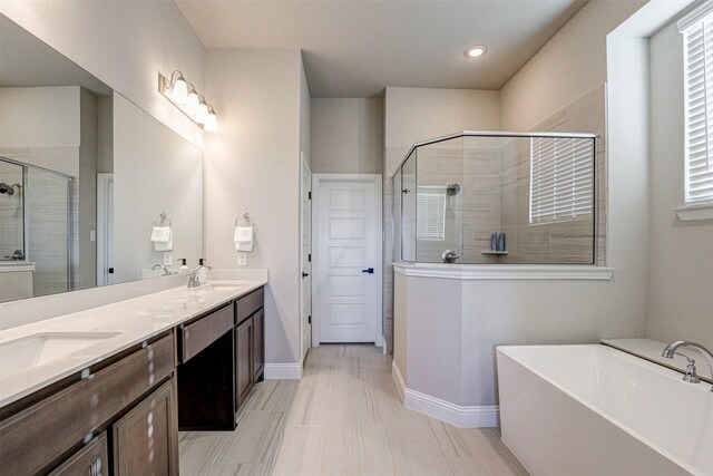 full bathroom featuring baseboards, a sink, a shower stall, a freestanding tub, and double vanity