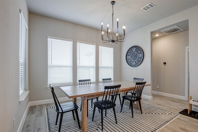dining space with baseboards, a notable chandelier, light wood finished floors, and visible vents