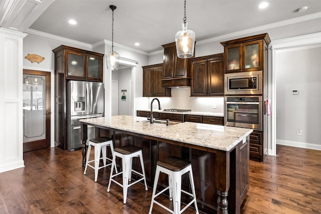 kitchen featuring dark brown cabinetry, dark wood finished floors, appliances with stainless steel finishes, and tasteful backsplash