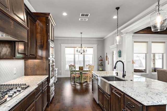 kitchen with dark wood-style floors, a sink, ornamental molding, appliances with stainless steel finishes, and tasteful backsplash