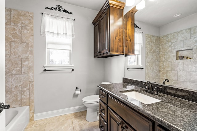 bathroom with a healthy amount of sunlight, toilet, vanity, and baseboards