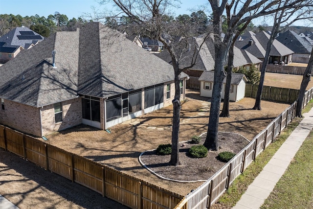 exterior space featuring an outbuilding, a residential view, a fenced backyard, and a sunroom