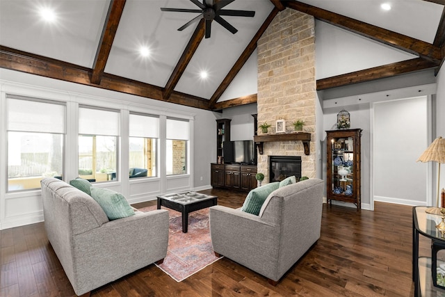 living room with beamed ceiling, high vaulted ceiling, dark wood-style flooring, a stone fireplace, and a decorative wall