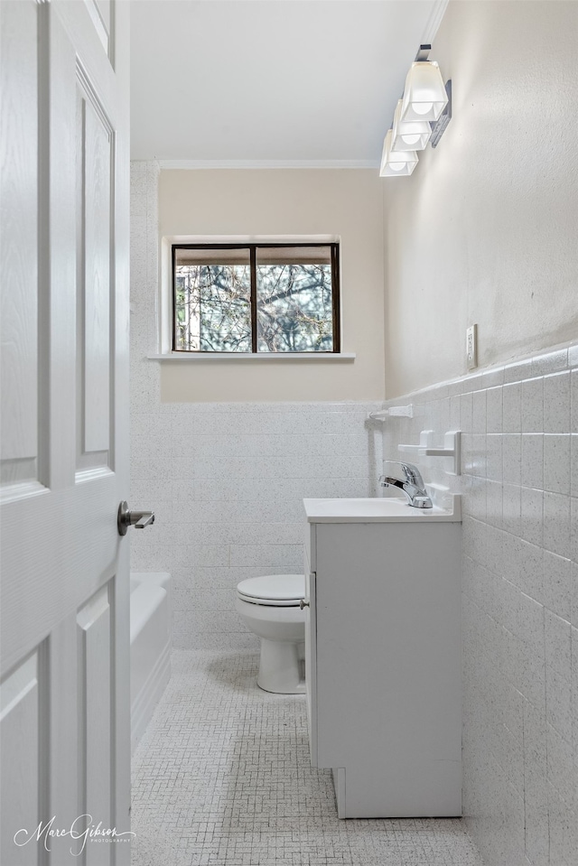 full bathroom with tile walls, a wainscoted wall, toilet, tile patterned floors, and vanity