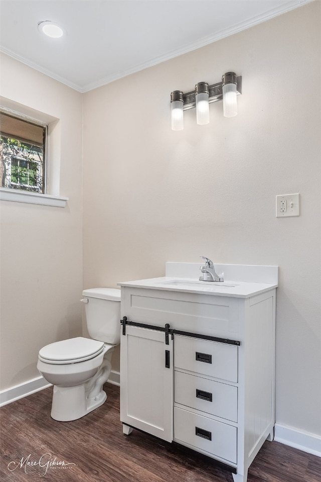 bathroom featuring toilet, wood finished floors, crown molding, baseboards, and vanity