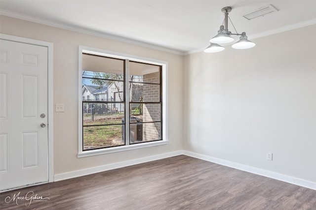 unfurnished dining area with visible vents, baseboards, ornamental molding, an inviting chandelier, and wood finished floors