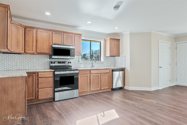 813 Dalzell St, Shreveport, LA 71104 - kitchen with stainless steel appliances, wood finished floors, decorative backsplash, ornamental molding, and recessed lighting