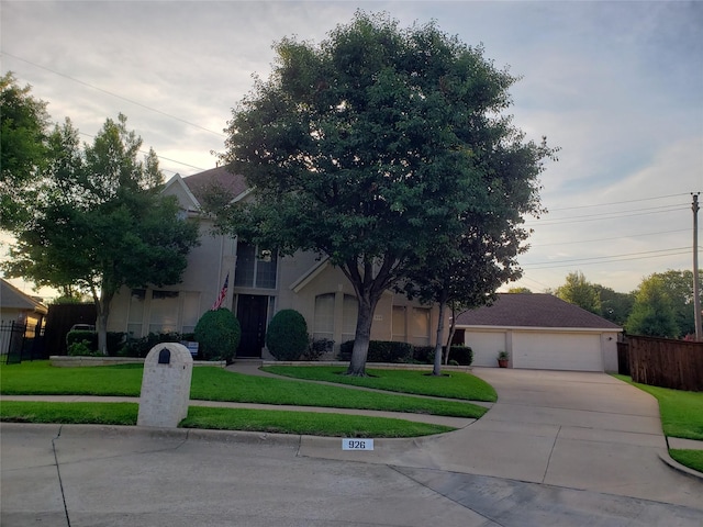 obstructed view of property with a front yard, fence, a detached garage, and stucco siding