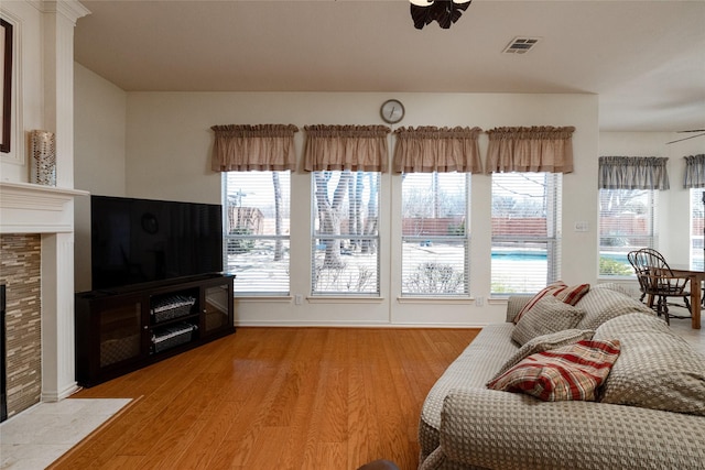 living room featuring ceiling fan, visible vents, wood finished floors, and a fireplace