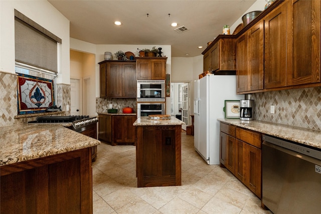 kitchen featuring tasteful backsplash, visible vents, a kitchen island, light stone countertops, and stainless steel appliances