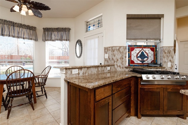 kitchen featuring stainless steel gas cooktop, light stone counters, tasteful backsplash, and a ceiling fan