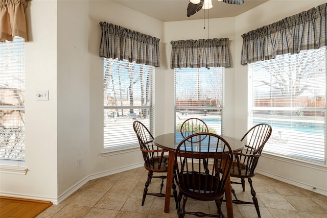 dining space featuring baseboards, ceiling fan, and light tile patterned flooring