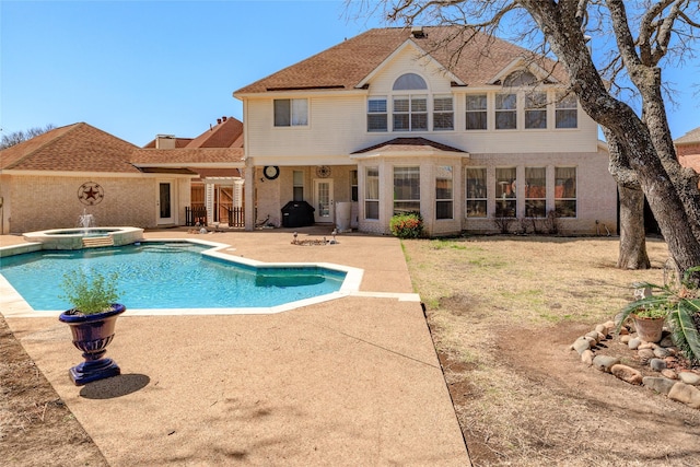 back of property featuring a pool with connected hot tub and a patio