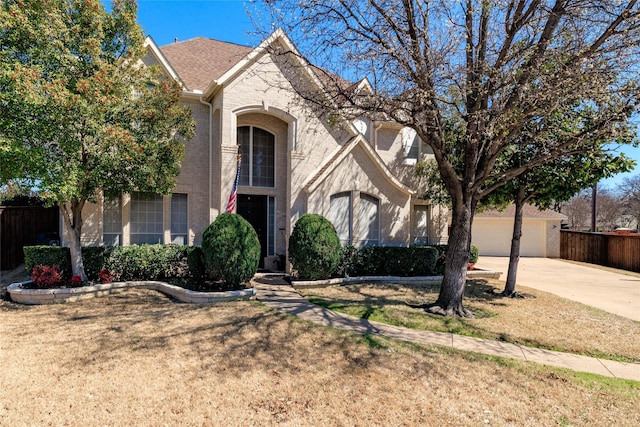 view of front of home featuring concrete driveway, fence, brick siding, and a front yard