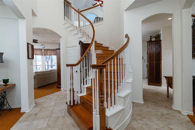 stairs with baseboards, arched walkways, and a towering ceiling