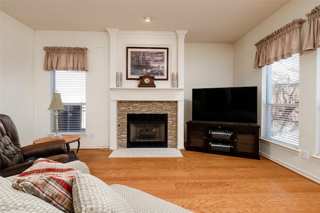 living area with a tiled fireplace, baseboards, and wood finished floors