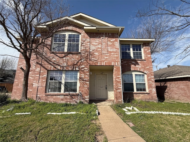 traditional-style home featuring brick siding and a front yard